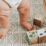 Baby leger med træklodser på et tæppe.